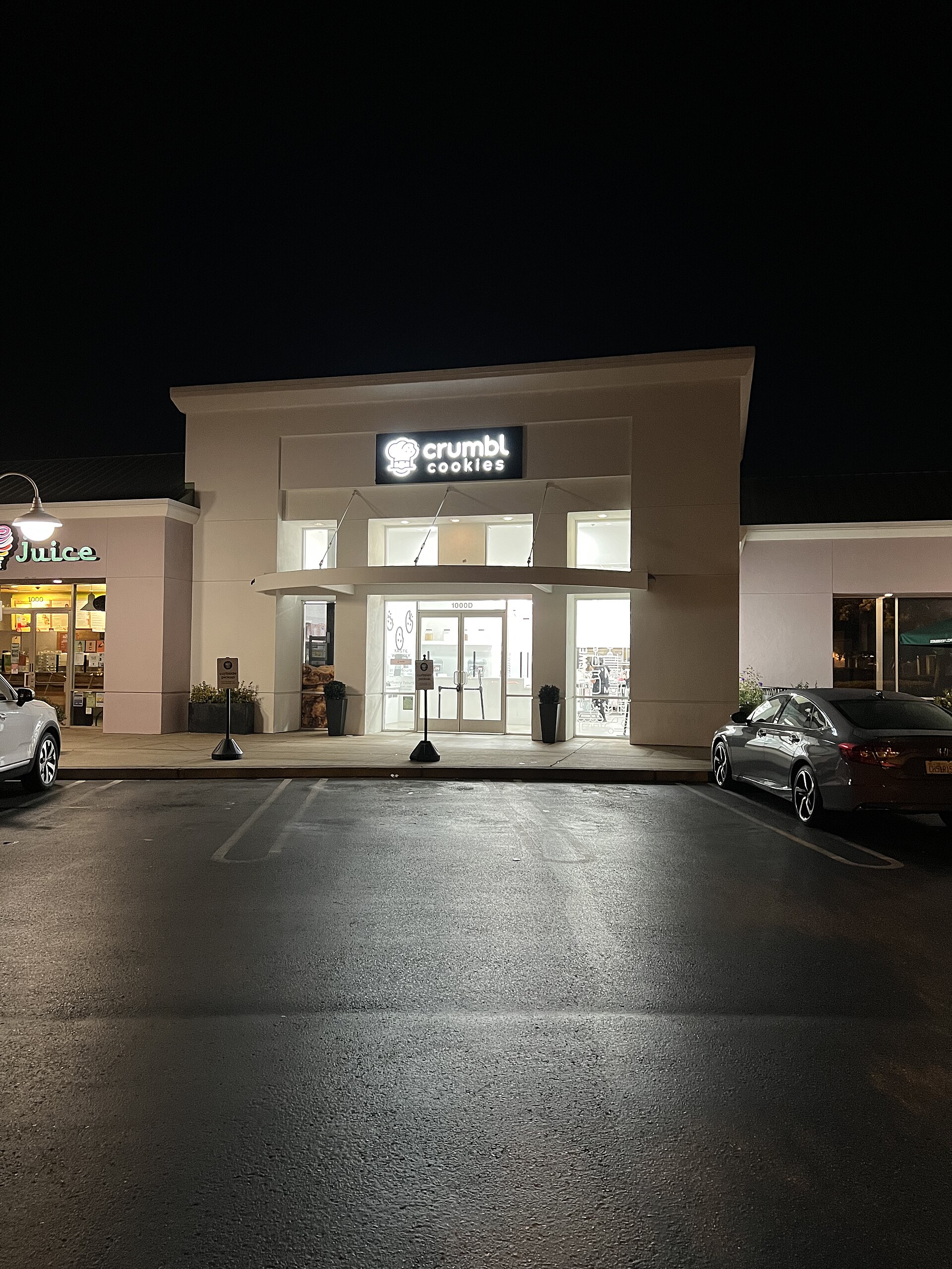 Crumbl Cookies storefront at night with illuminated sign and entrance