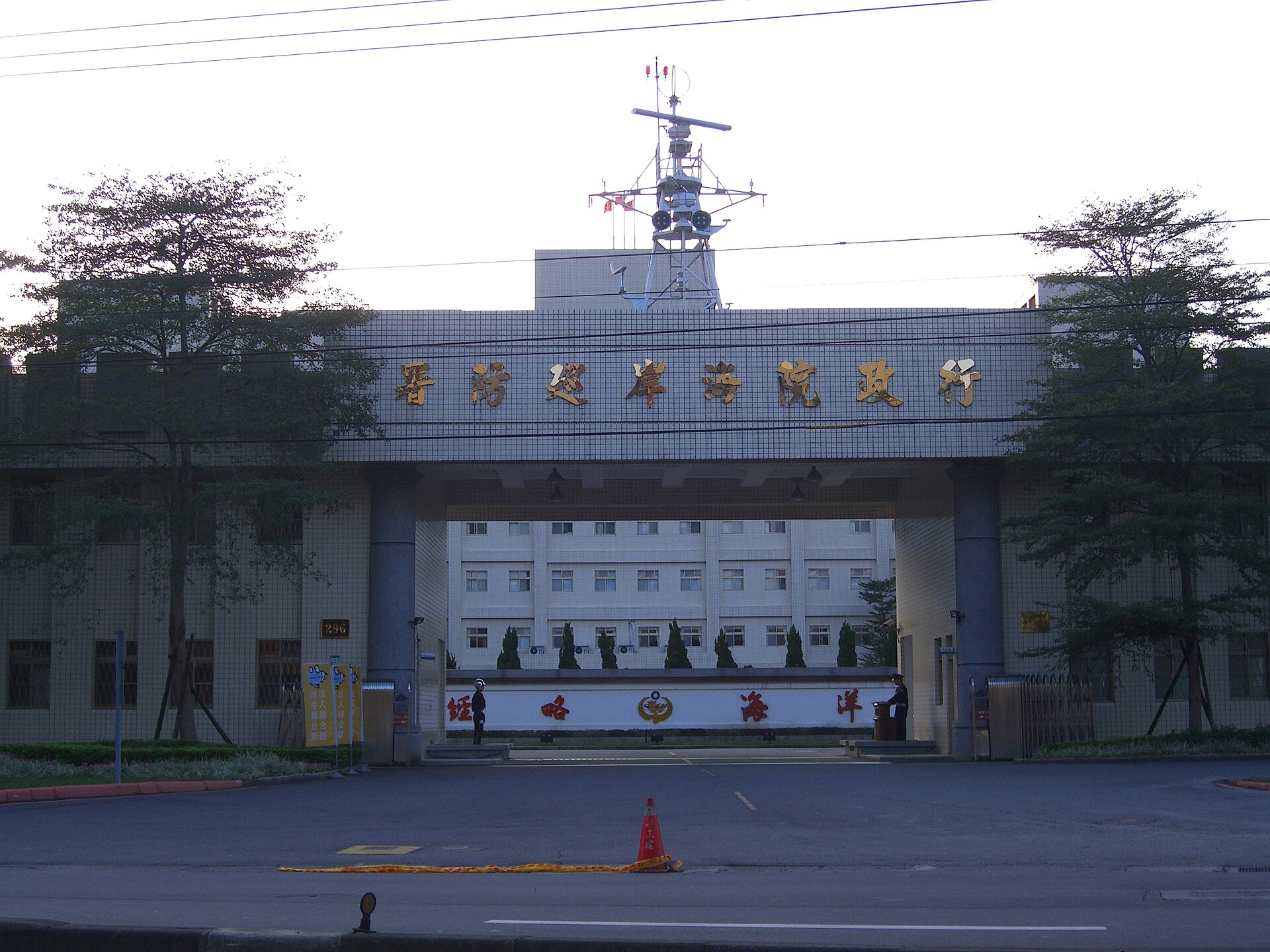 A building with Chinese characters above an archway, with trees on either side and a clear sky above.