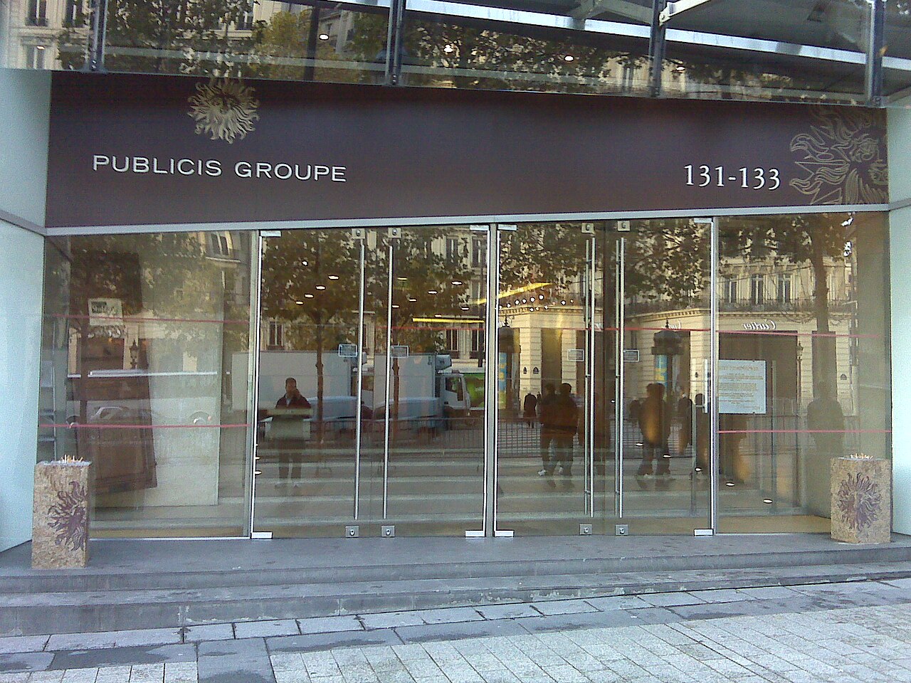 The exterior of a Publicis Groupe building with the company name and address 131-133 visible above glass doors.