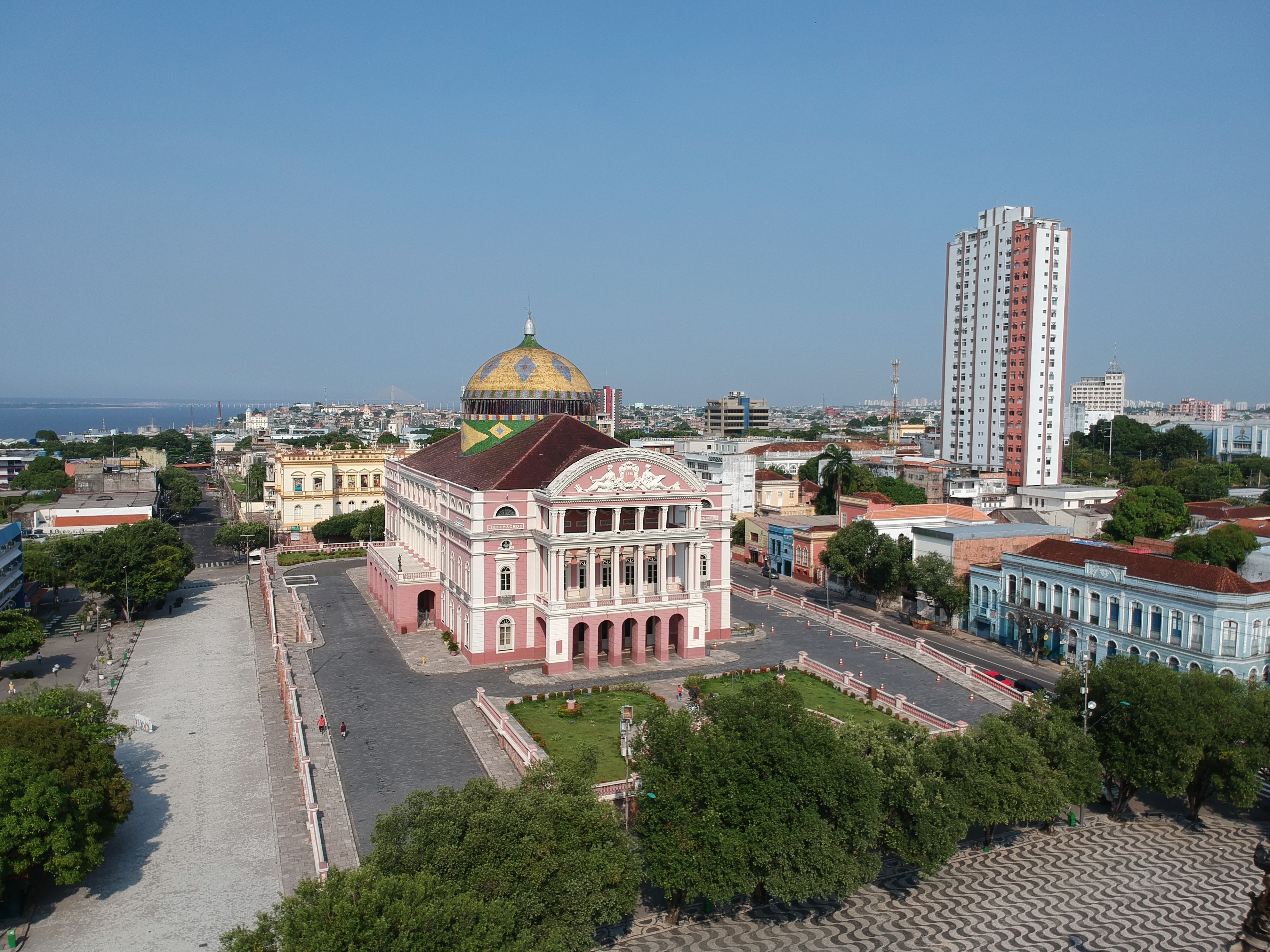 The Amazon Theatre in Manaus, Brazil, a pink opera house with a dome, seen across a plaza.