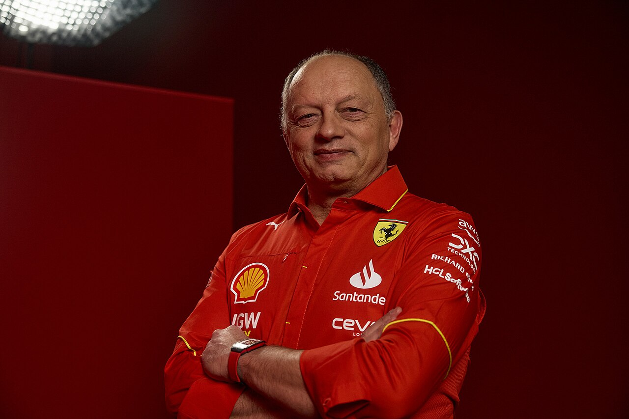 man in red shirt with logos and arms crossed