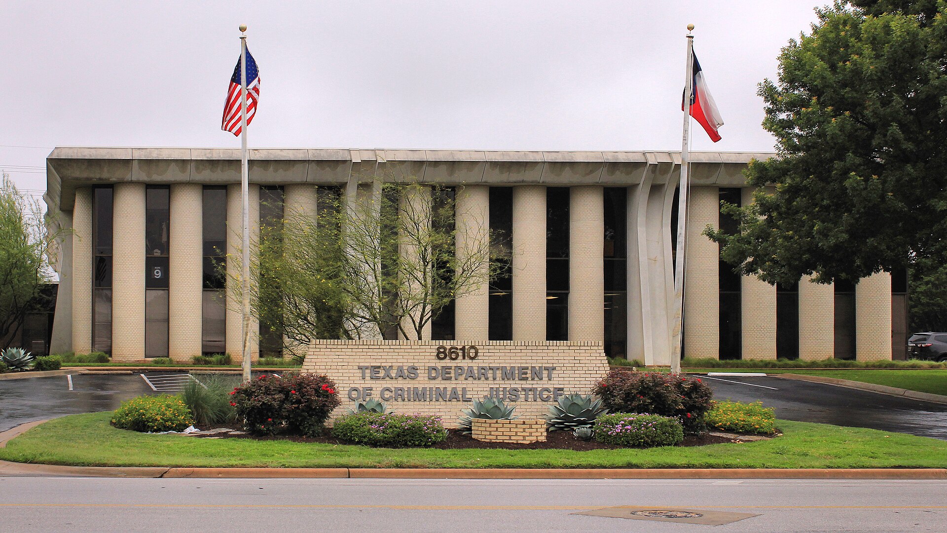 The Texas Department of Criminal Justice building with flags and landscaping.