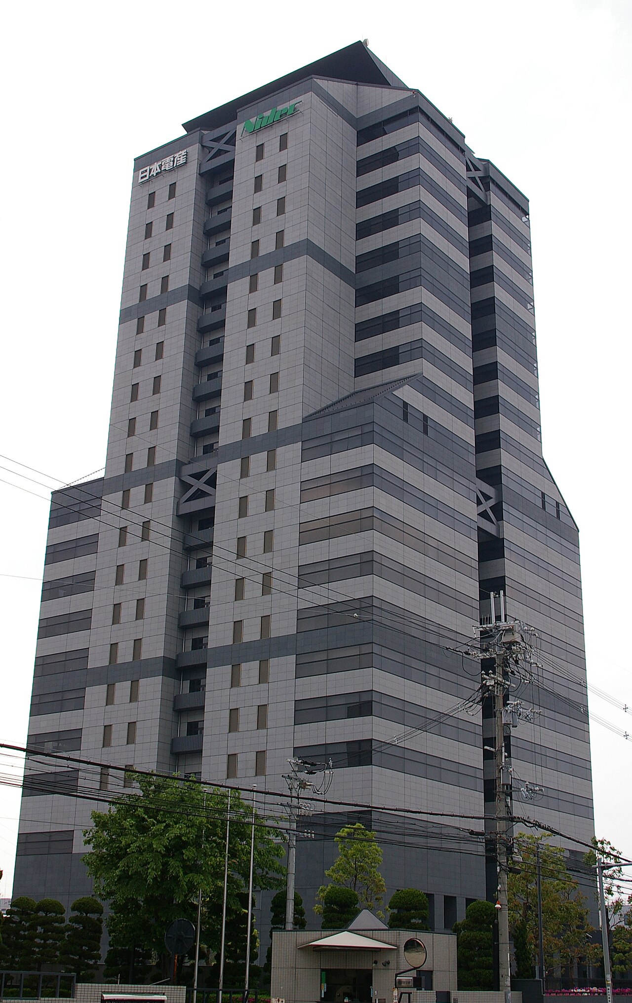 A tall gray building with a green logo reading Nidec and Japanese characters on the top left corner.