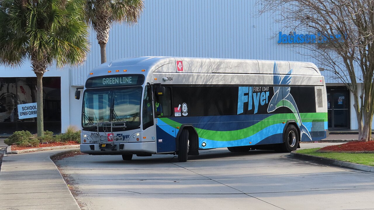 A bus labeled Flyer and Green Line is parked in front of a building with a sign that reads Jacksonville Transit Authority.
