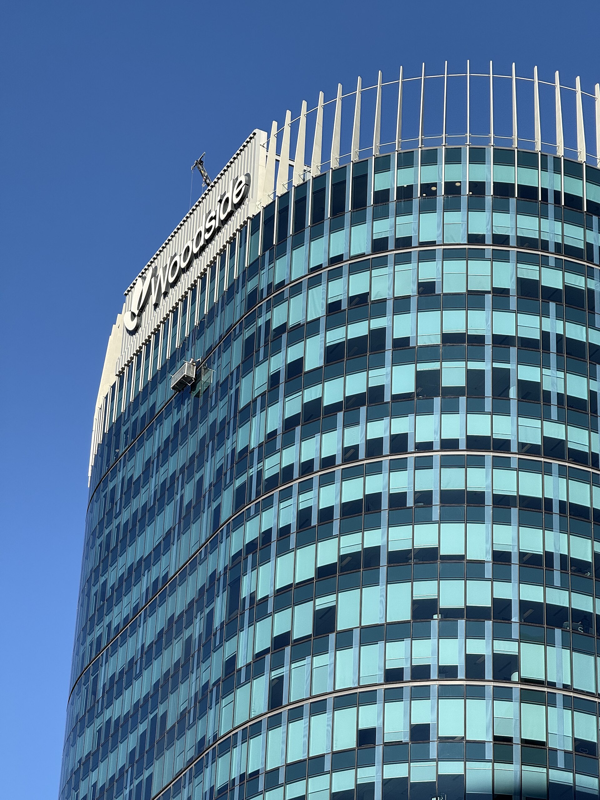 A modern glass-fronted office building with the Woodside logo visible at the top.