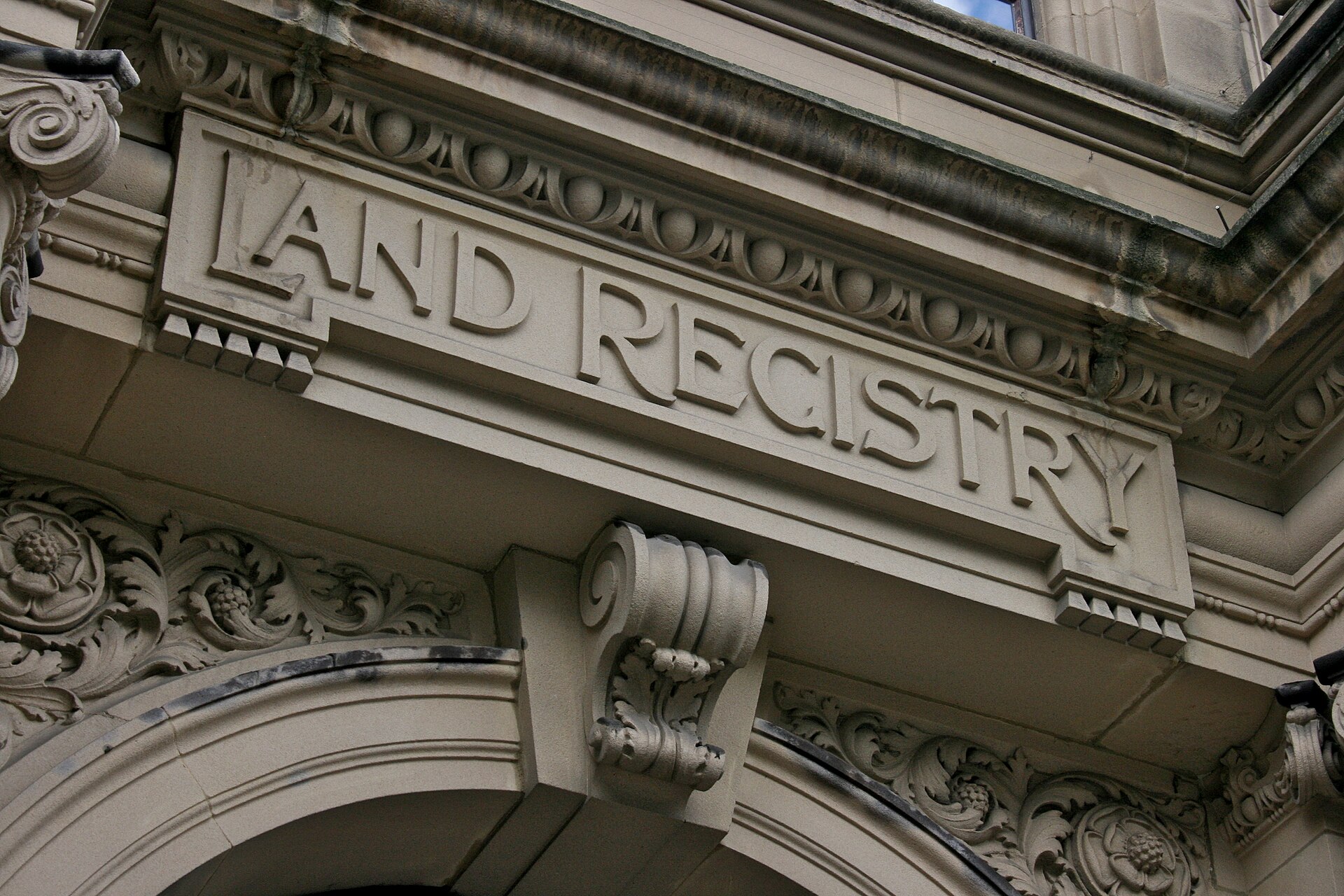 The words "LAND REGISTRY" are carved in large, raised letters on the facade of a building, above an ornate archway.
