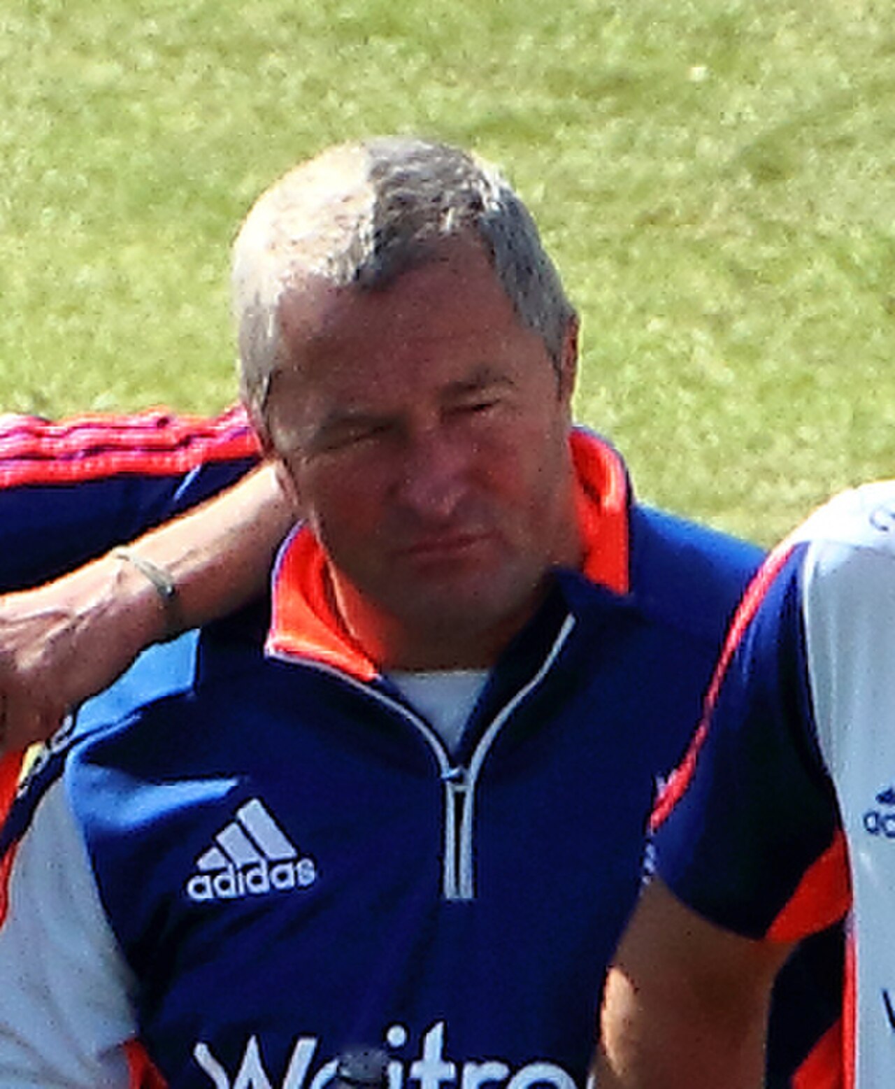 A middle-aged man with short gray hair wearing a blue and orange Adidas shirt