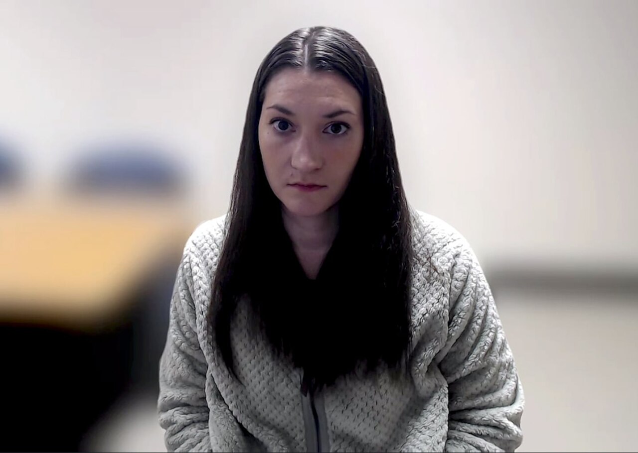 A woman with long dark hair wearing a gray sweater