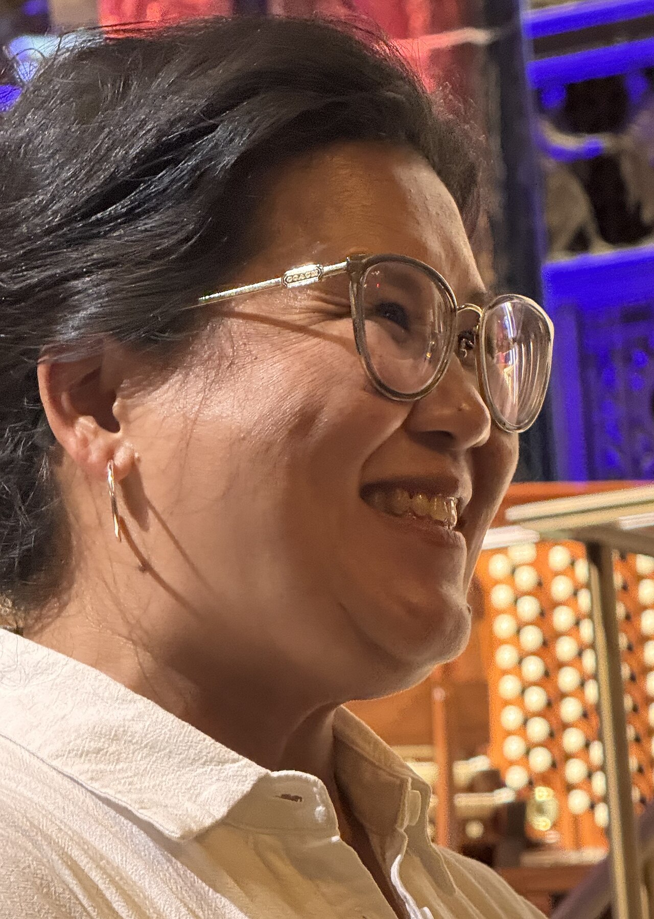 St. Paul Mayor Kaohly Her, wearing glasses and a white shirt, smiling at an indoor event.