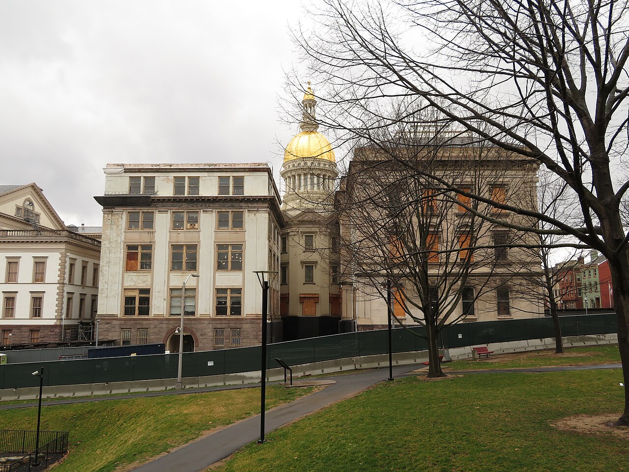 The New Jersey State House in Trenton with its gold dome, seen across a lawn with bare trees.