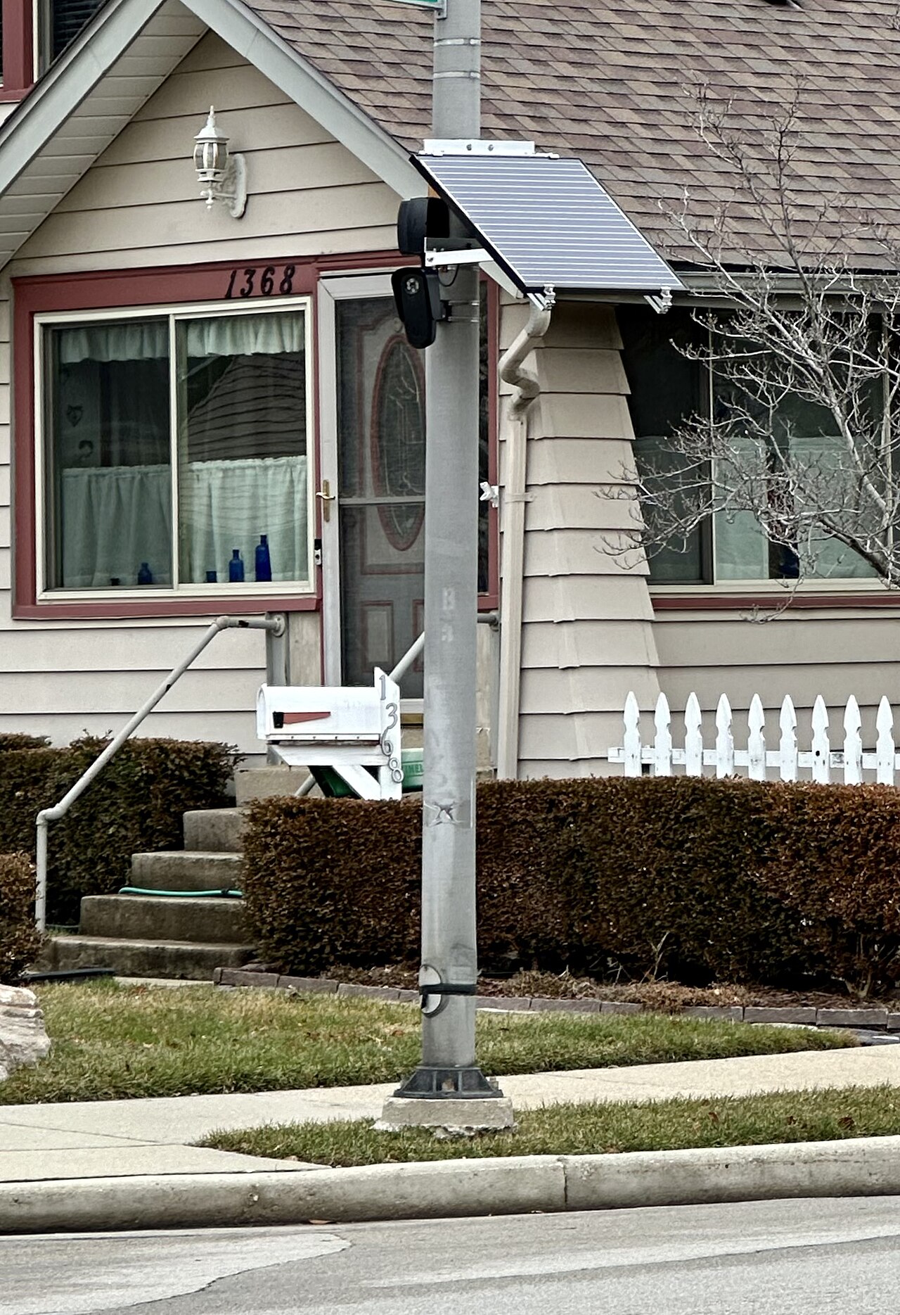 A Flock Safety camera mounted on a pole in front of a house.