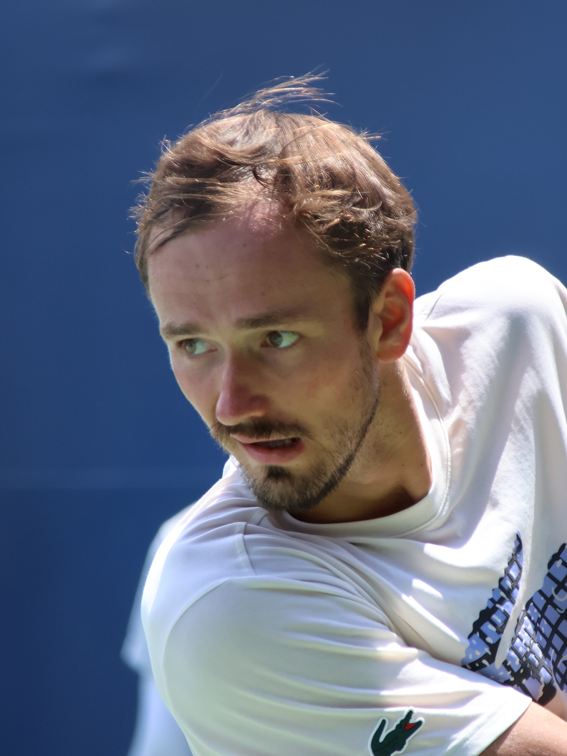 Daniil Medvedev in a white shirt looking towards the camera