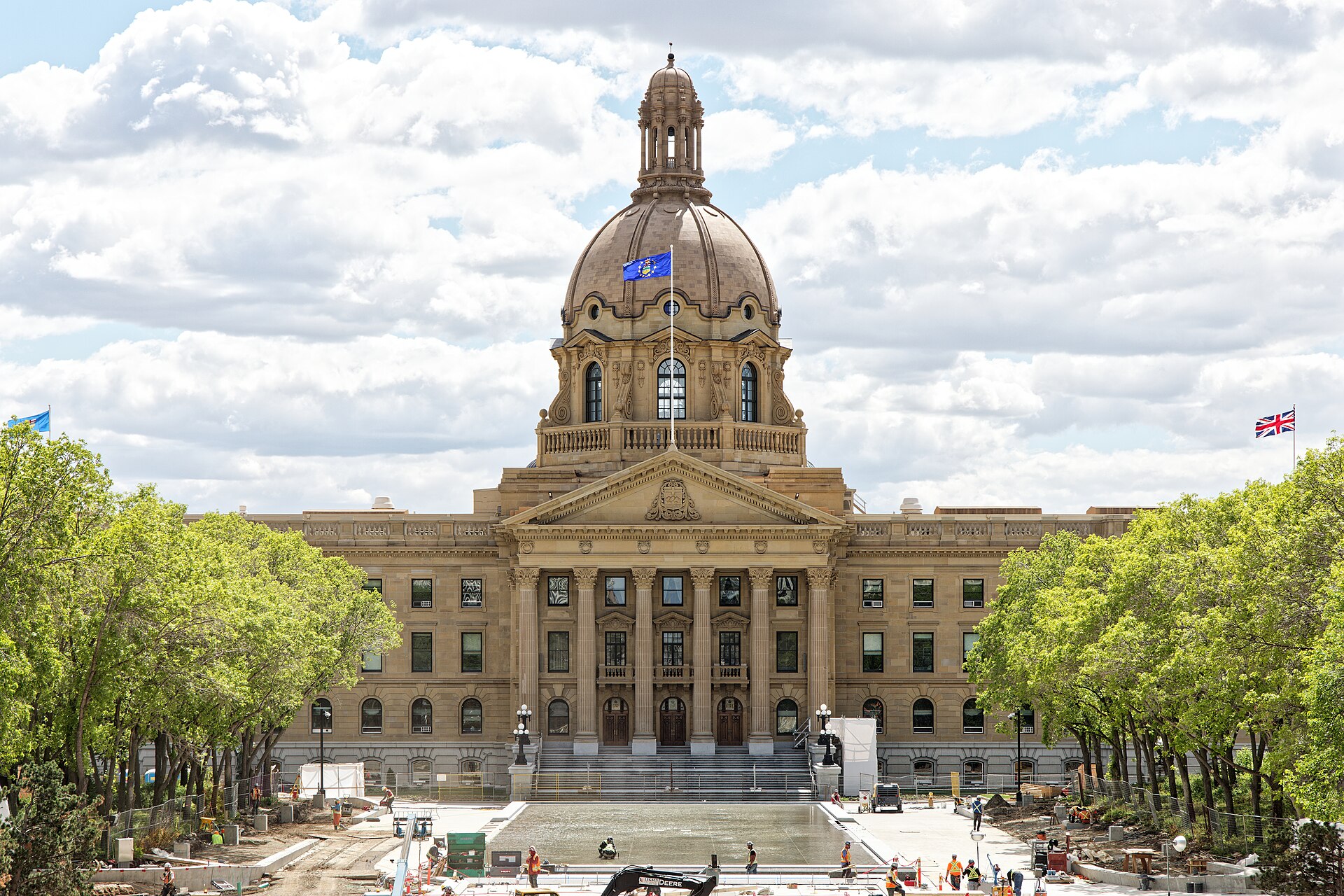The Alberta Legislature Building in Edmonton, Canada, under a cloudy sky, with trees and construction in the foreground.