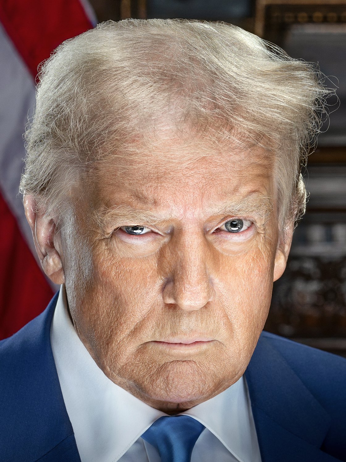 Official 2025 headshot of Donald Trump in a blue suit, face centered, flag behind him.