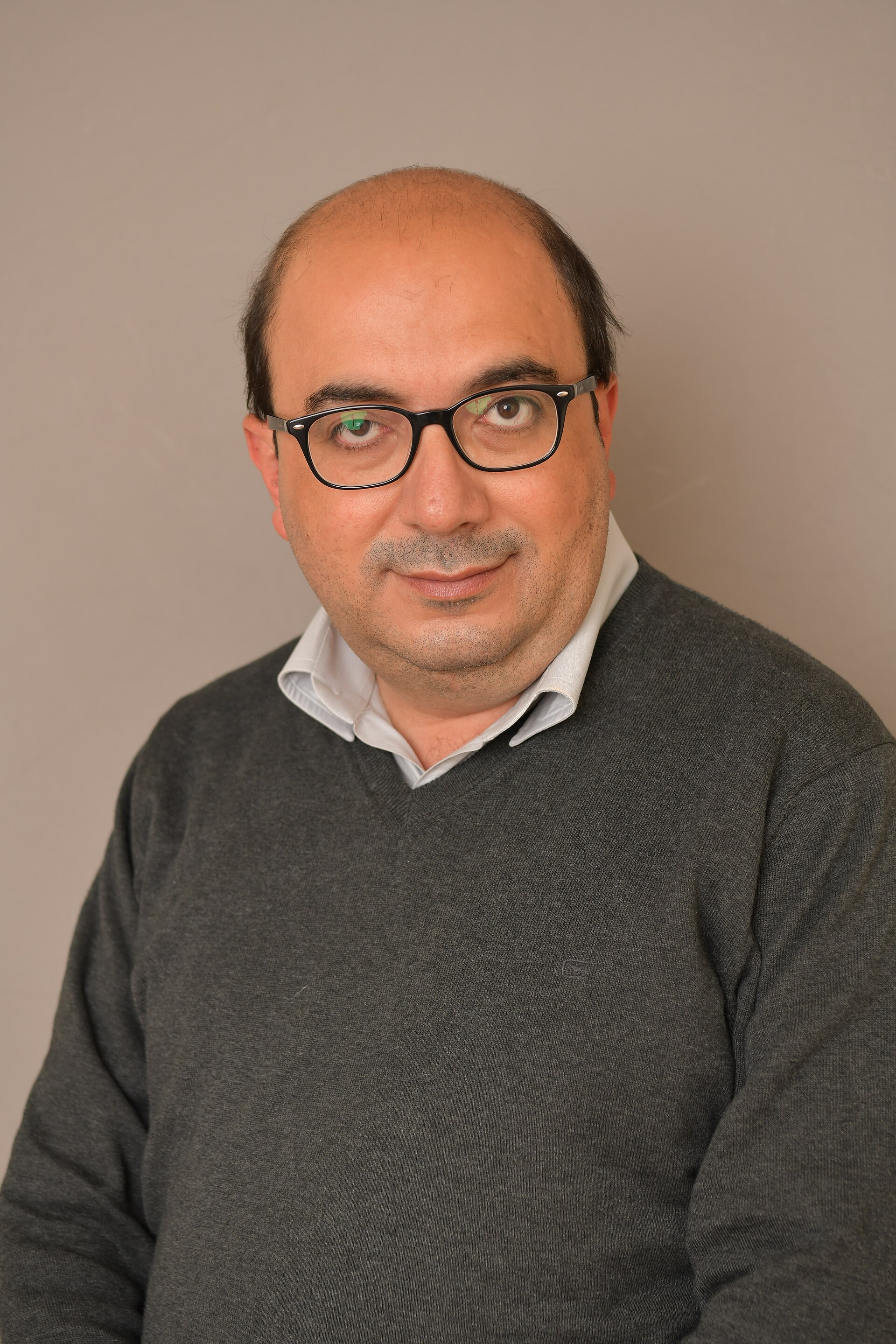 A man with glasses and a gray sweater