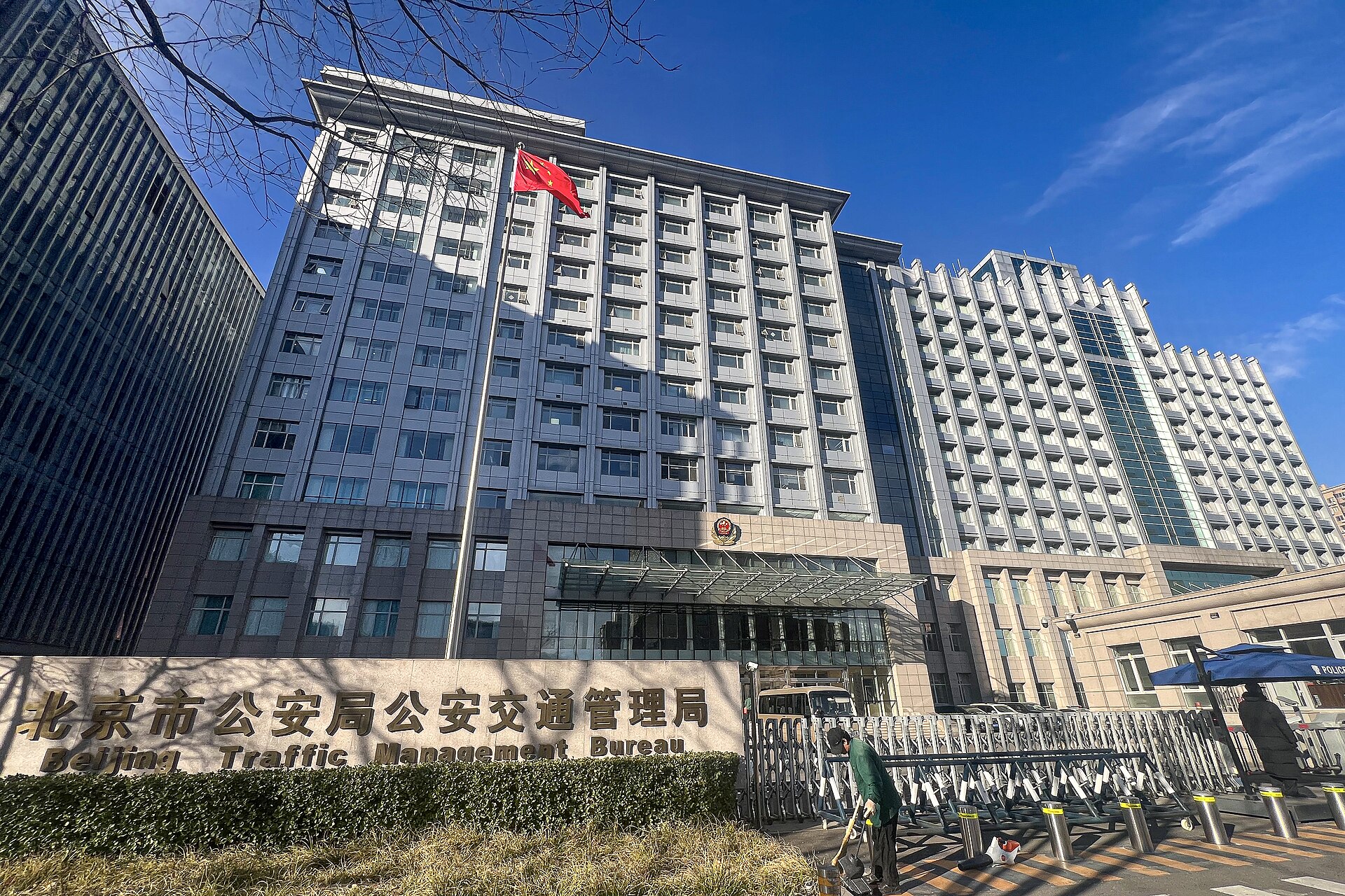 A large, modern office building with a Chinese flag flying from a flagpole on top. The building has many windows and a sign in both Chinese and English that reads "Beijing Traffic Management Bureau".