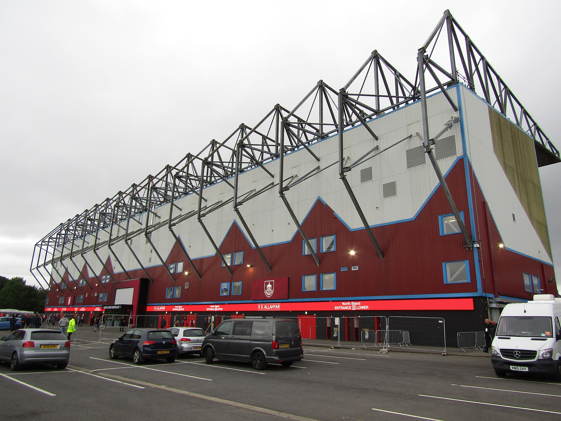 A large stadium with a red and white facade and a distinctive roof structure.
