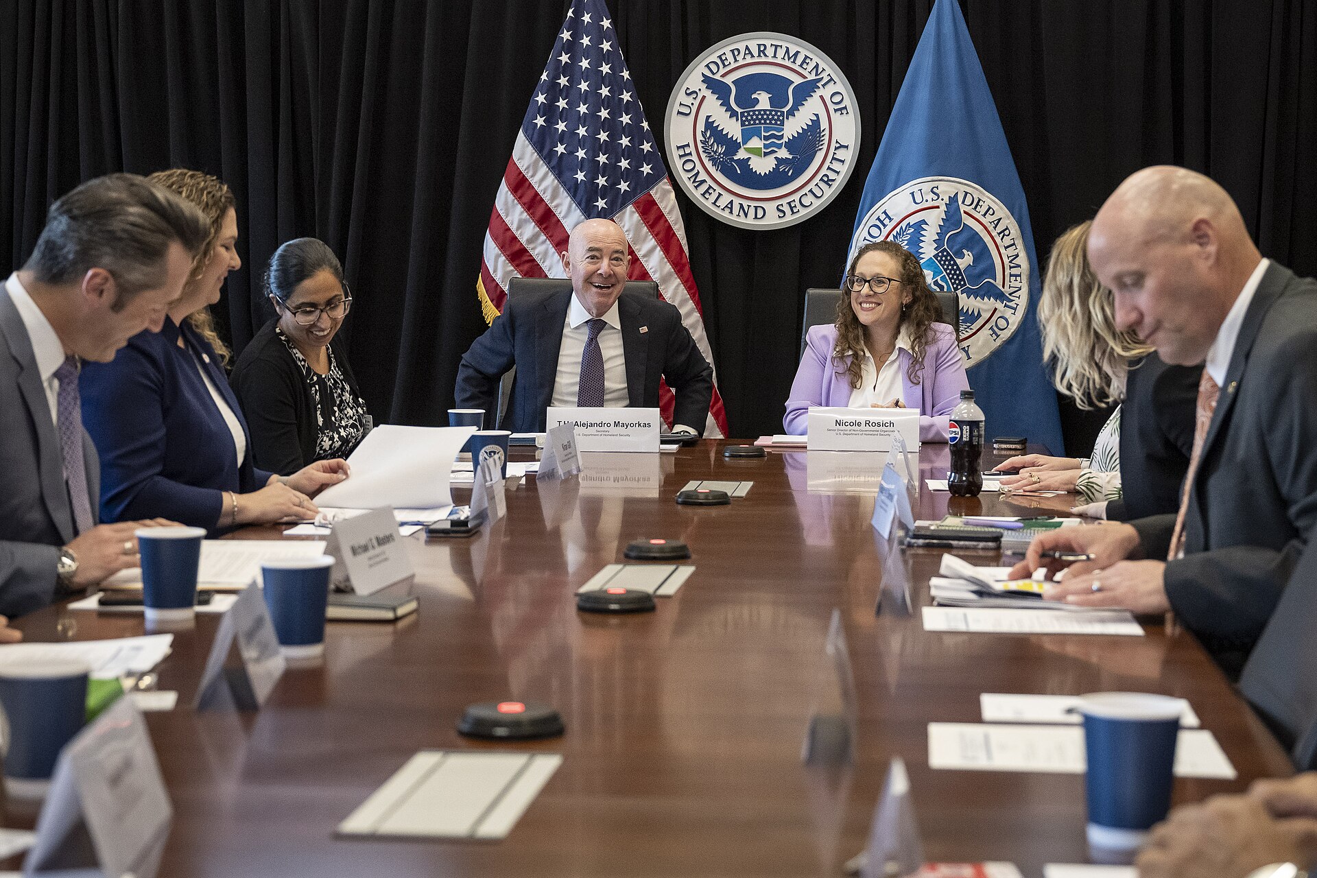 Alejandro Mayorkas, Secretary of the U.S. Department of Homeland Security, smiles while seated at a conference table with other officials, including Nicole Rosich, Senior Advisor of Non-Governmental Organizations to the U.S. Department of Homeland Security. The U.S. Department of Homeland Security s