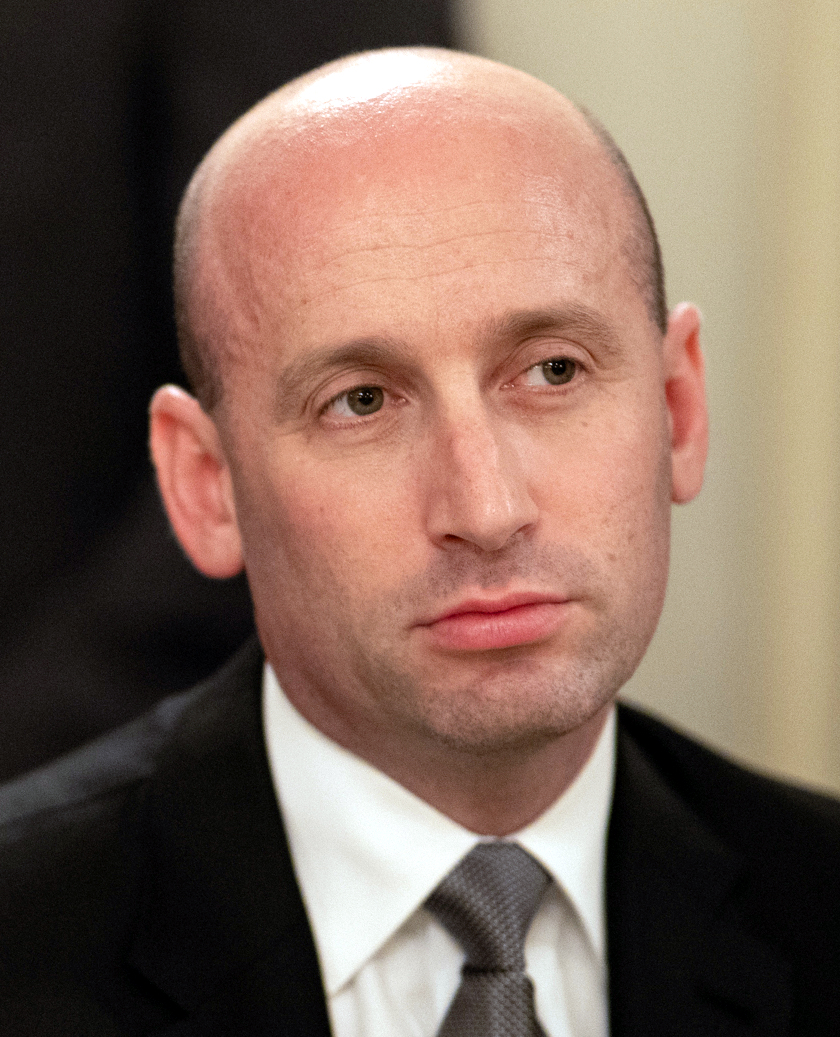 Stephen Miller in a dark suit, shown in a close-up portrait.