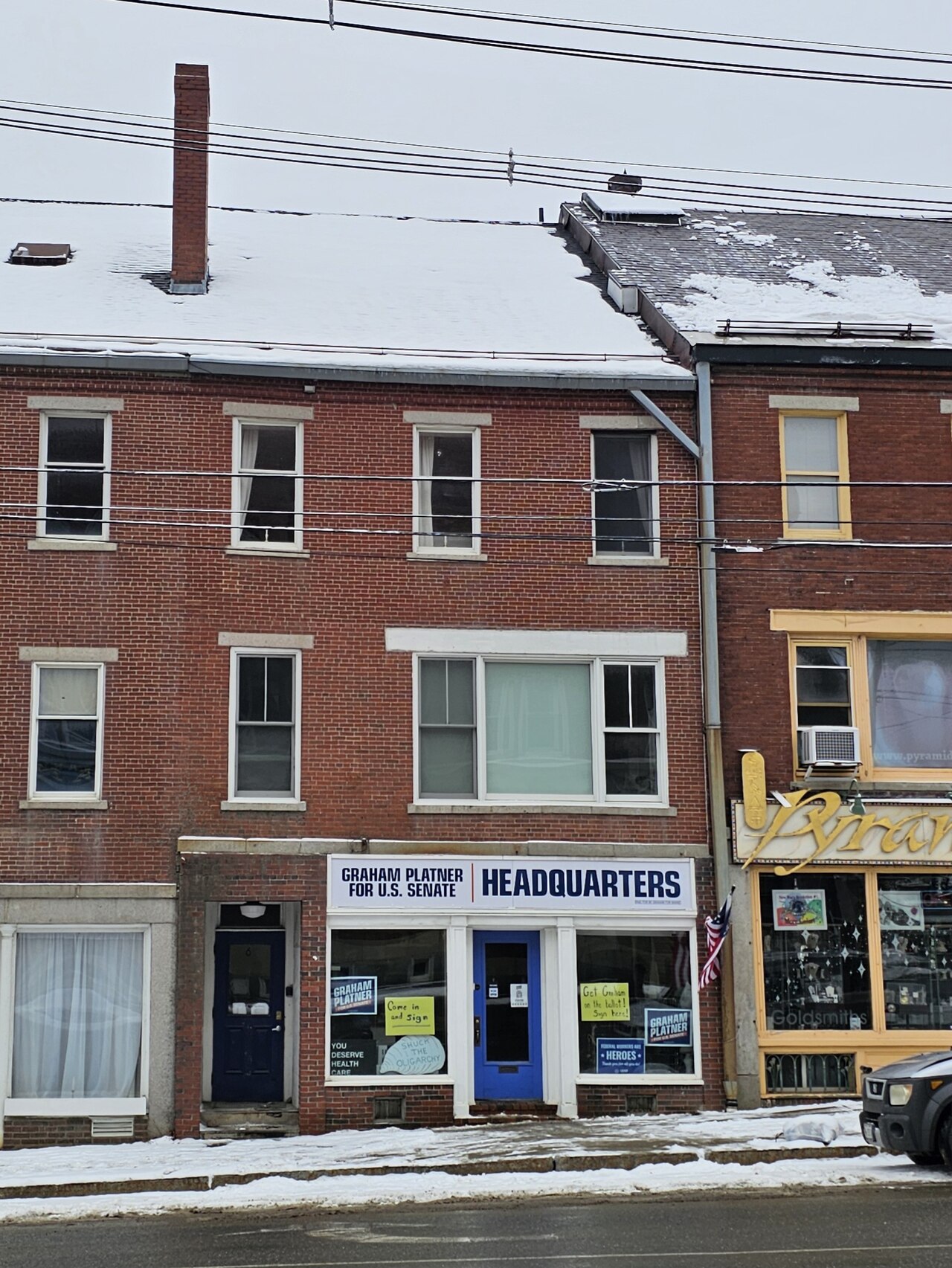 A red brick building with a white sign that reads Graham Platner for U.S. Senate Headquarters