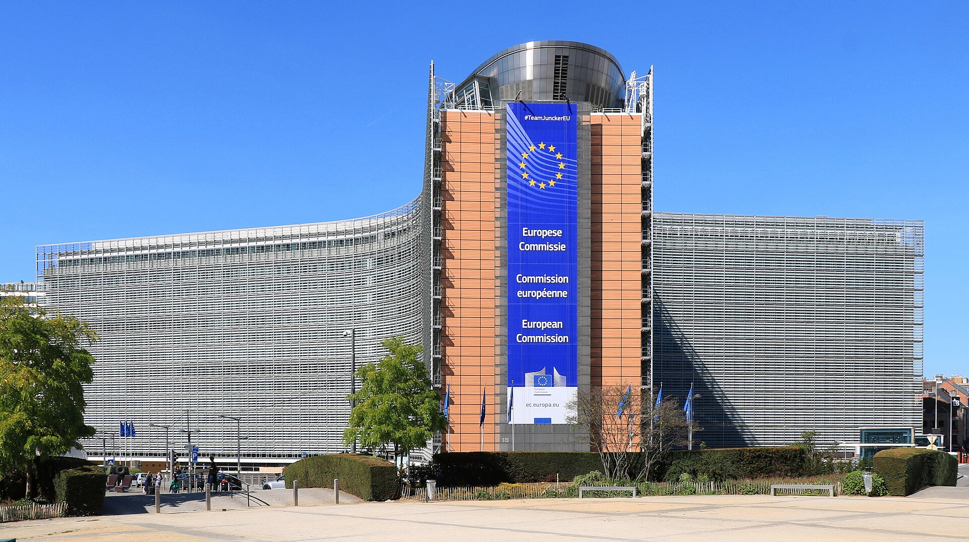 European Commission building with a large blue banner displaying the European Commission logo and text in multiple languages
