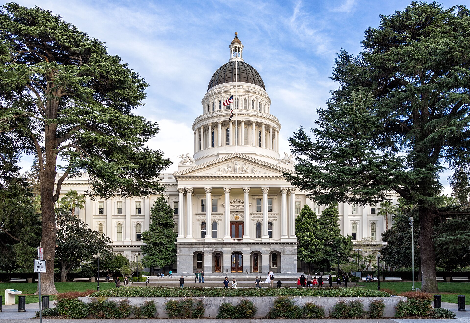 California State Capitol building with dome and columns surrounded by trees and people
