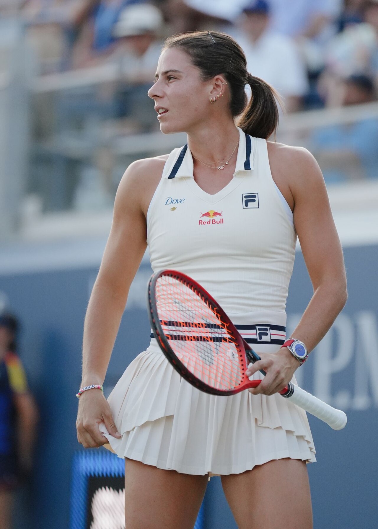 A female tennis player in a white outfit holding a tennis racket