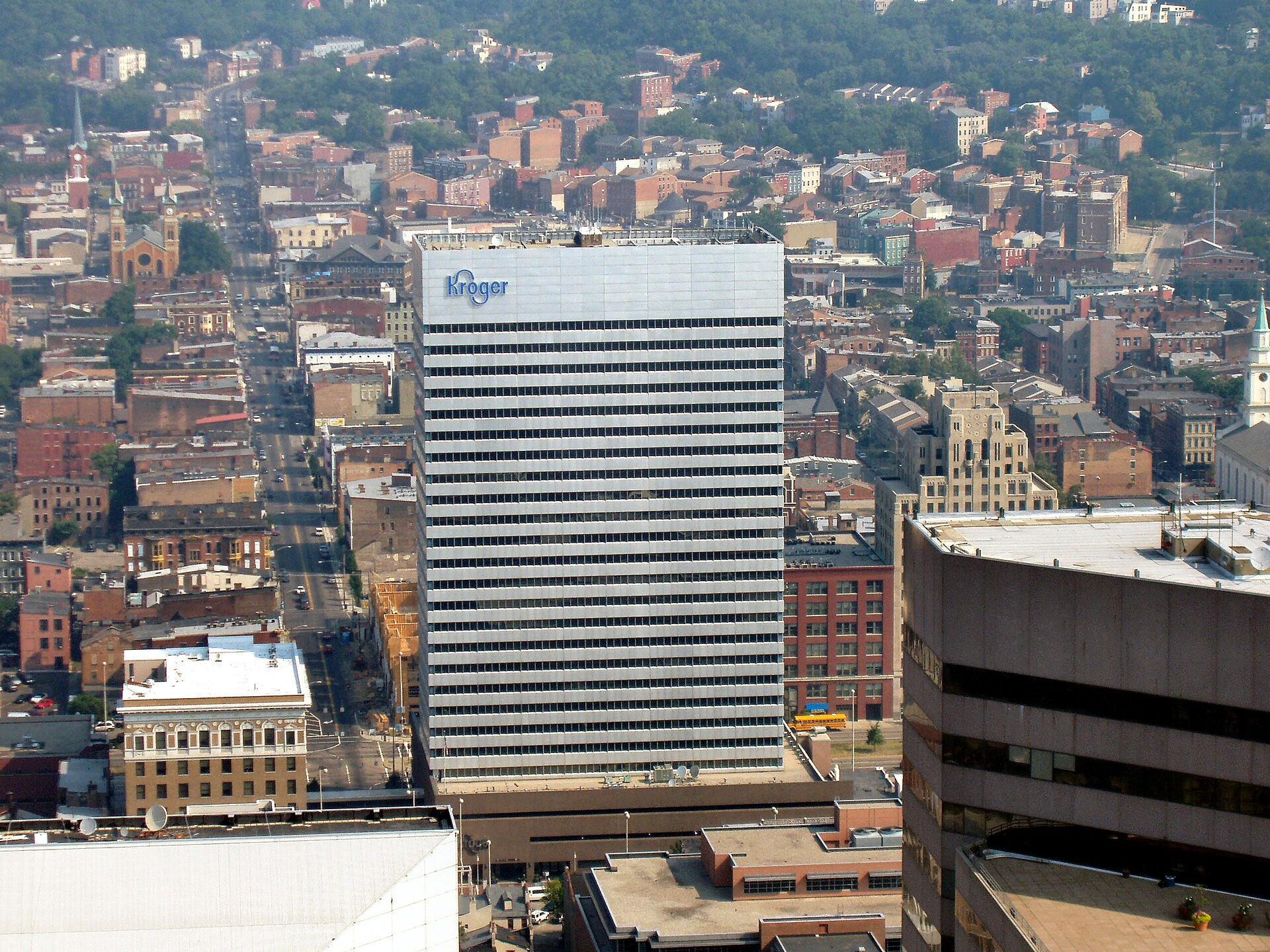 Aerial view of a city with a tall building in the center featuring a blue Kroger sign on its roof.