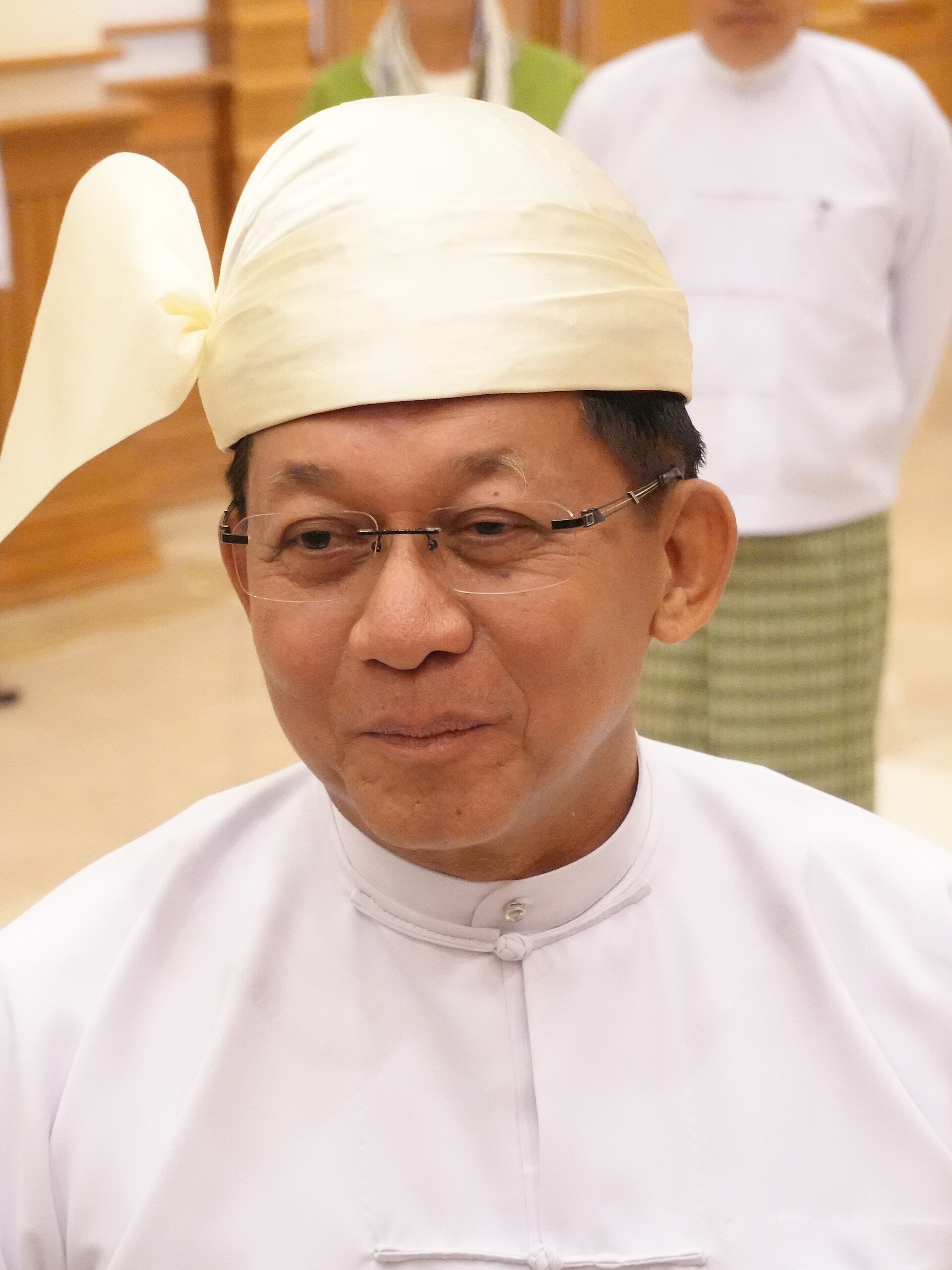 A man in a white shirt and head covering looks at the camera.