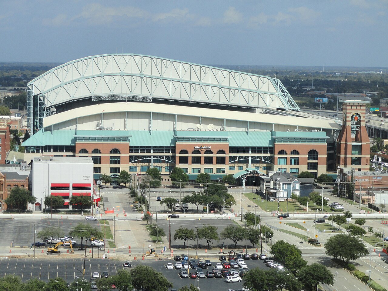 Aerial view of the Astros' ballpark in downtown Houston, with its arched roof over the stadium and parking lots in front.