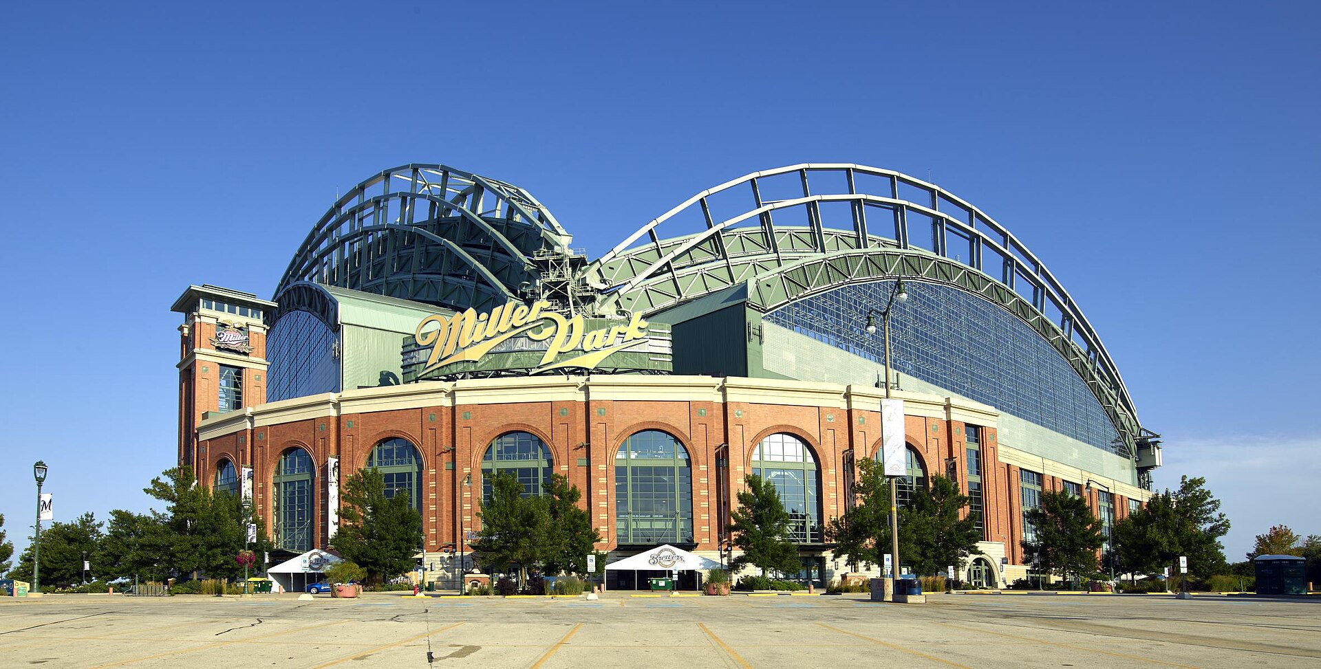 Miller Park, a large baseball stadium with a brick and glass facade, featuring a prominent yellow sign with the name