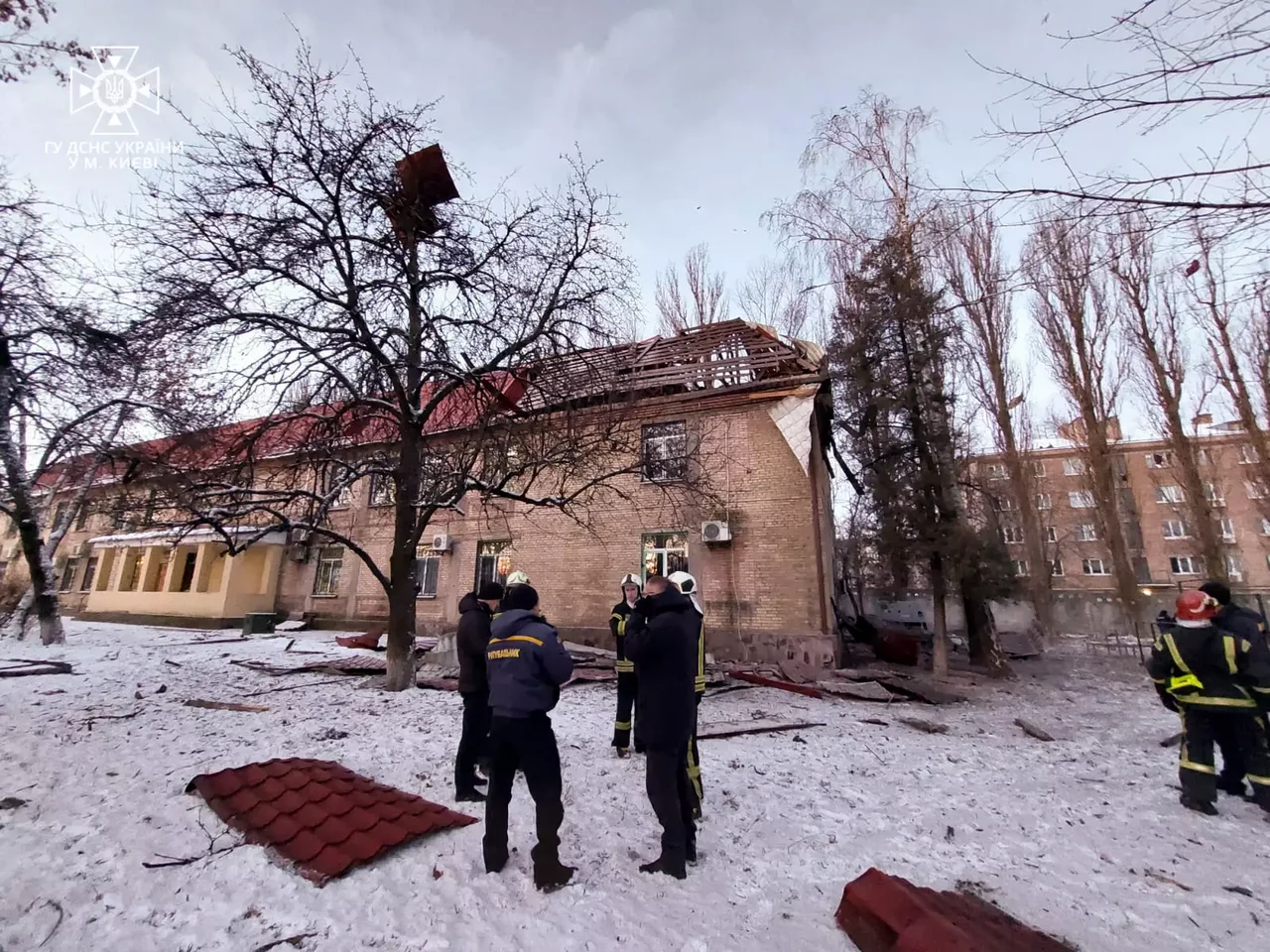 a damaged school building with people in uniforms standing outside