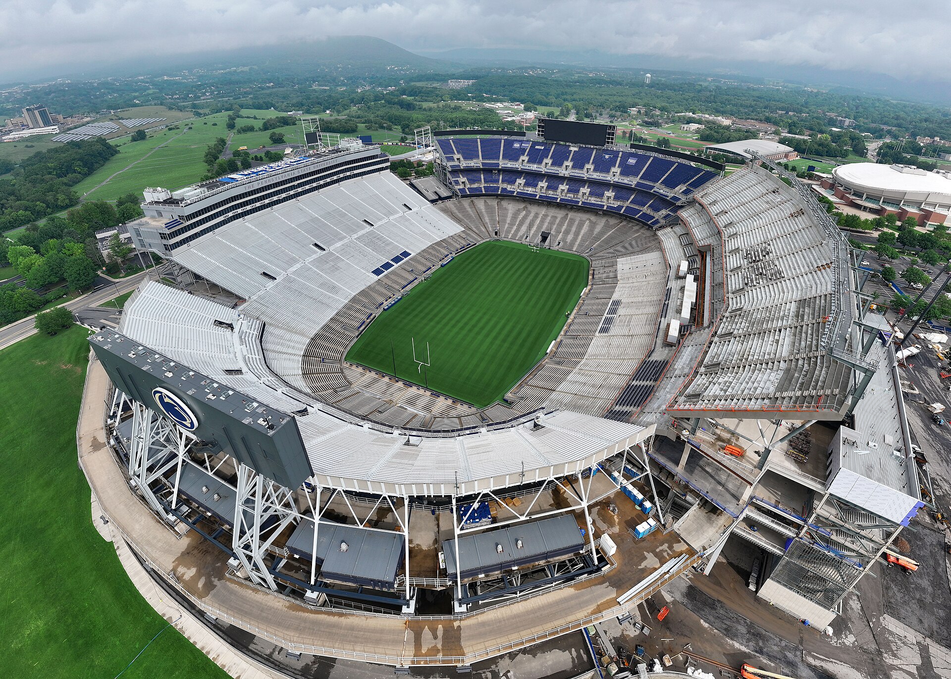 Aerial view of Beaver Stadium with green field and gray and blue seating