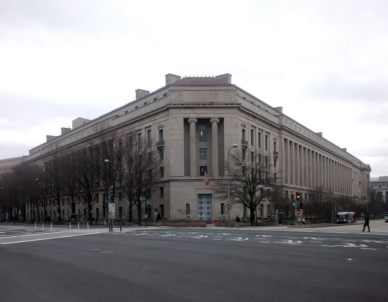The Robert F. Kennedy Department of Justice Building in Washington D.C. on a cloudy day, viewed from across a street intersection.