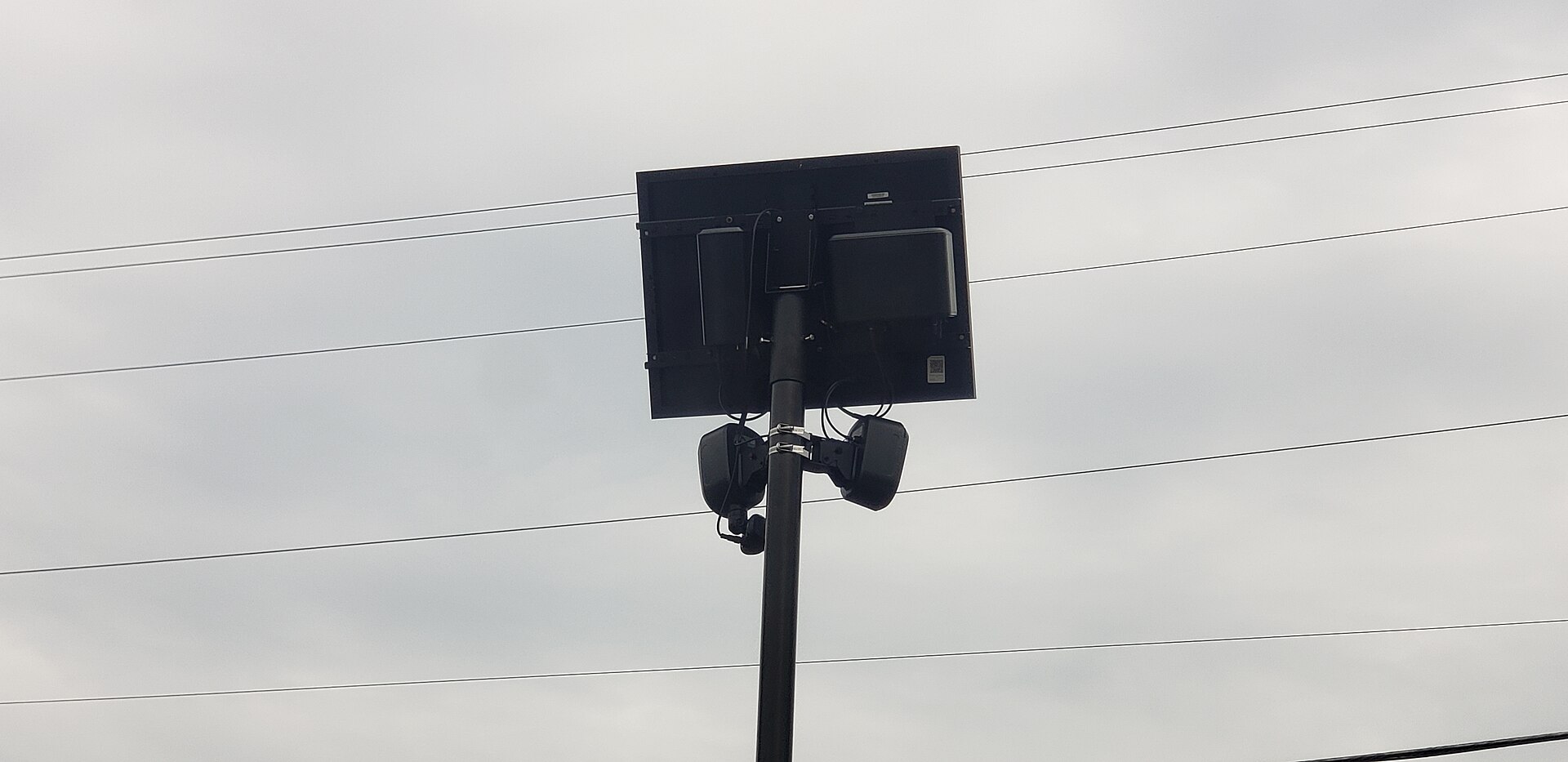 a black license plate reader on a pole with wires in the background