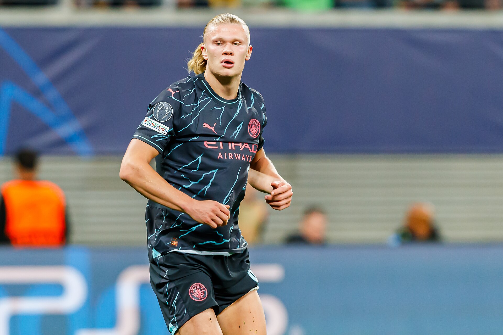 Erling Haaland in a Manchester City uniform running on a soccer field