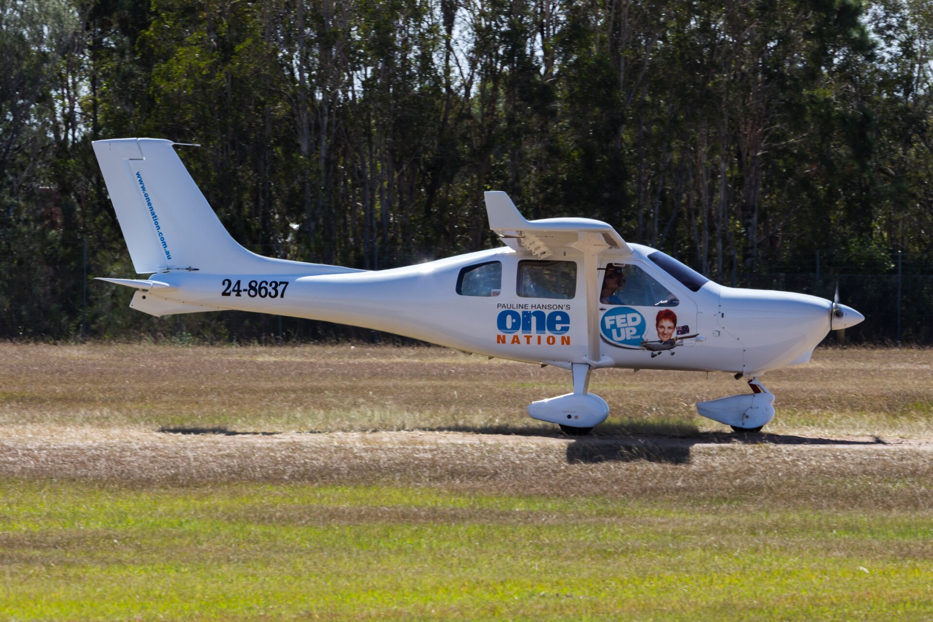 A white airplane with 'Pauline Hanson's One Nation' and 'Fed Up Tour' logos, and the registration number 24-8637, on a grassy field.