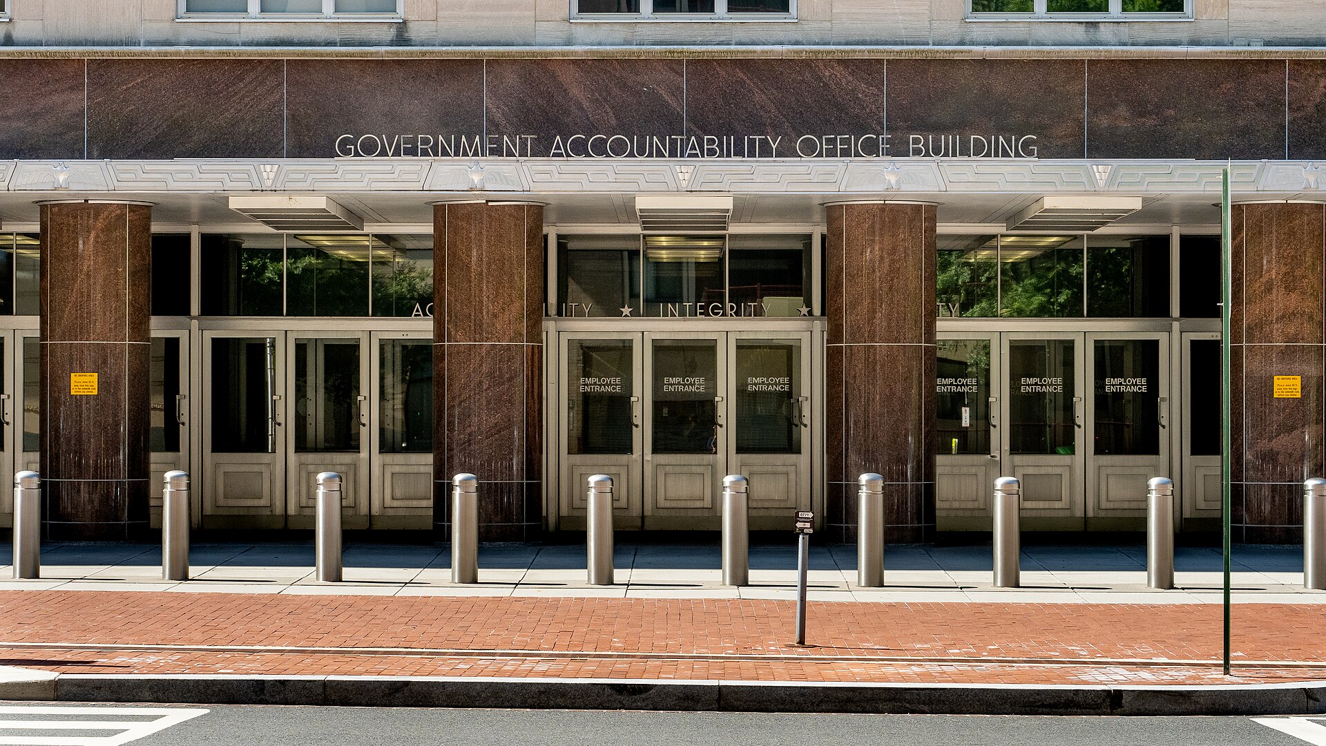 The entrance to the Government Accountability Office Building, featuring large glass doors labeled 'EMPLOYEE ENTRANCE' and marble columns.
