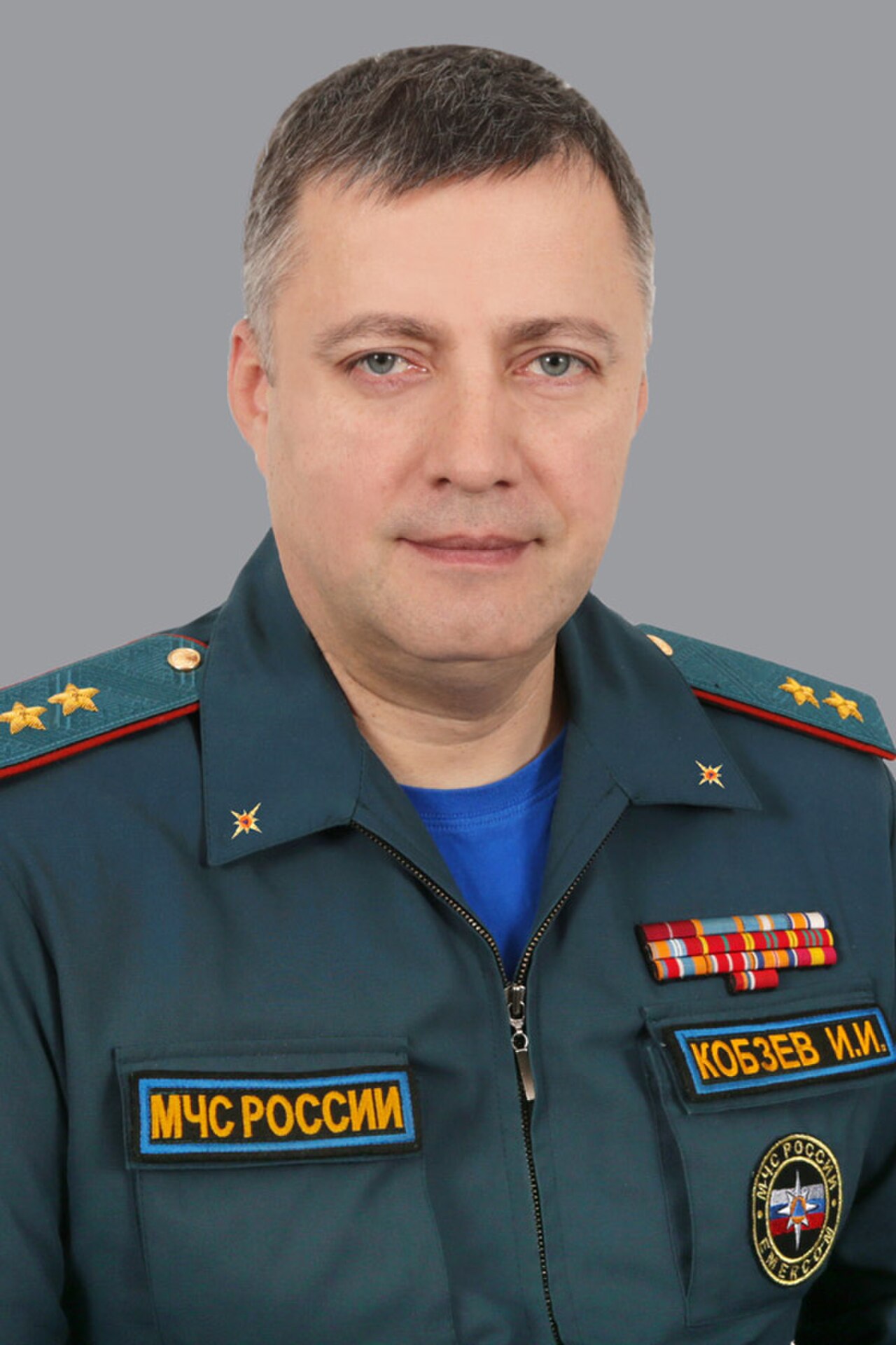 A middle-aged man in a green uniform with gold stars and patches, including one that reads KOBZEV