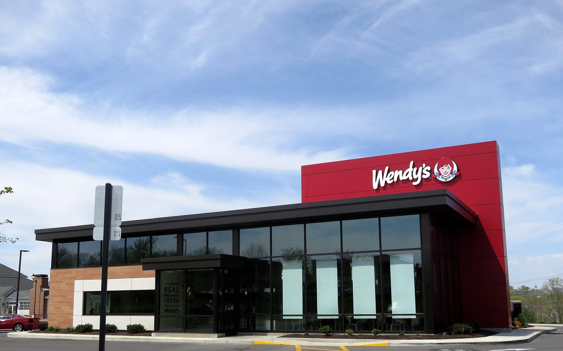 A red Wendy's restaurant building with large windows and a prominent Wendy's logo on the side.