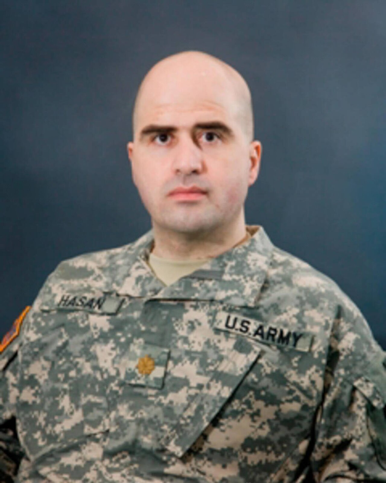 A bald man in a U.S. Army uniform with a name tag that reads Hasan.