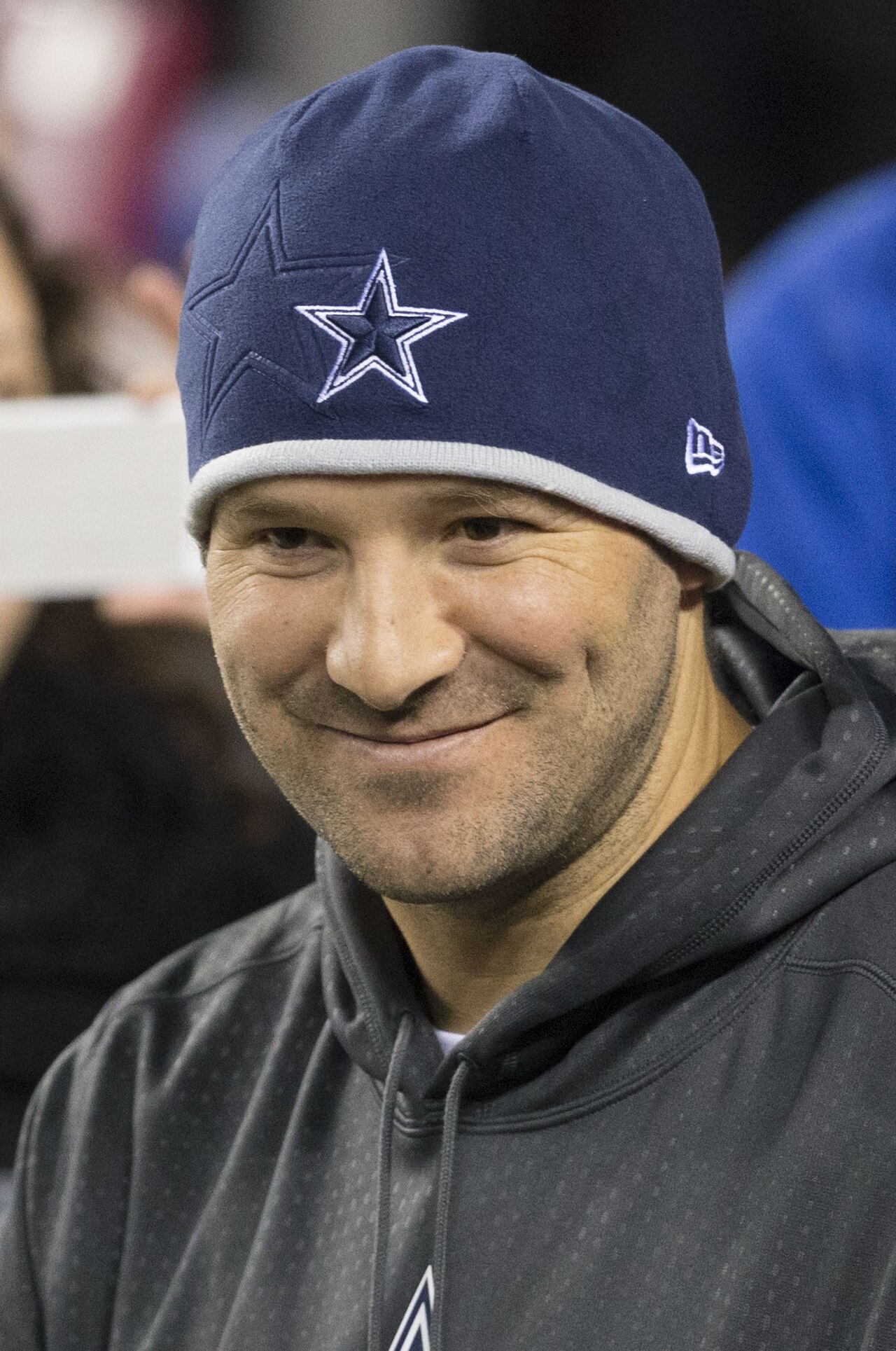 A smiling man wearing a blue beanie with a white star and a gray hoodie.
