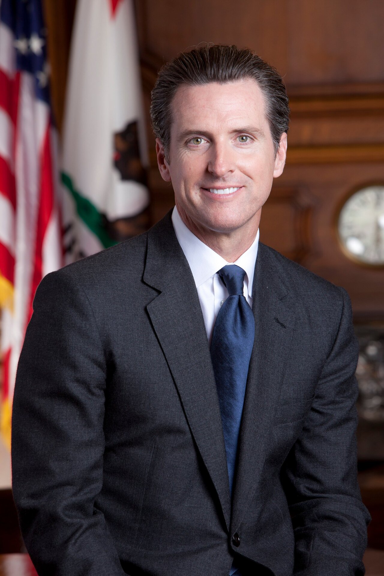 A man in a suit standing in front of flags
