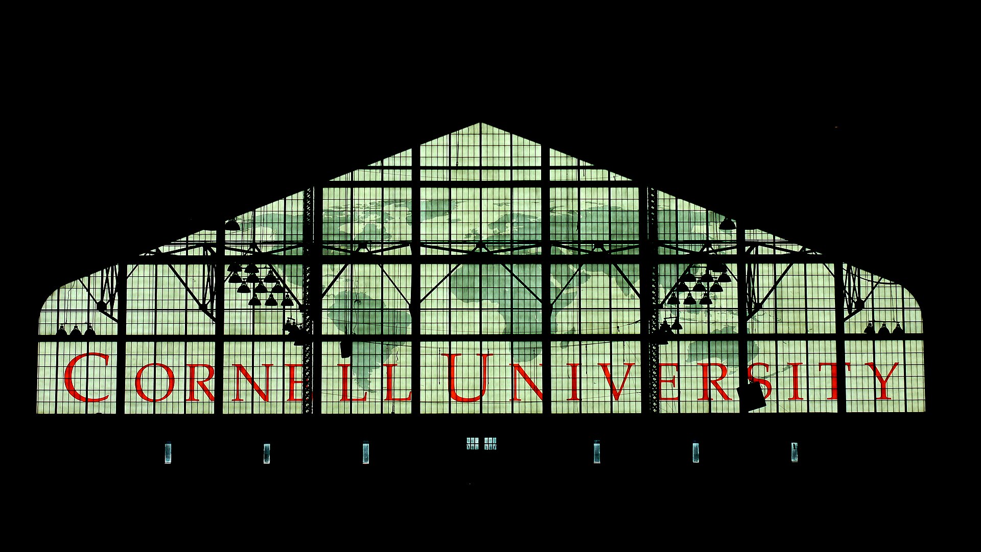 A large building with a glass facade and red lettering that reads Cornell University