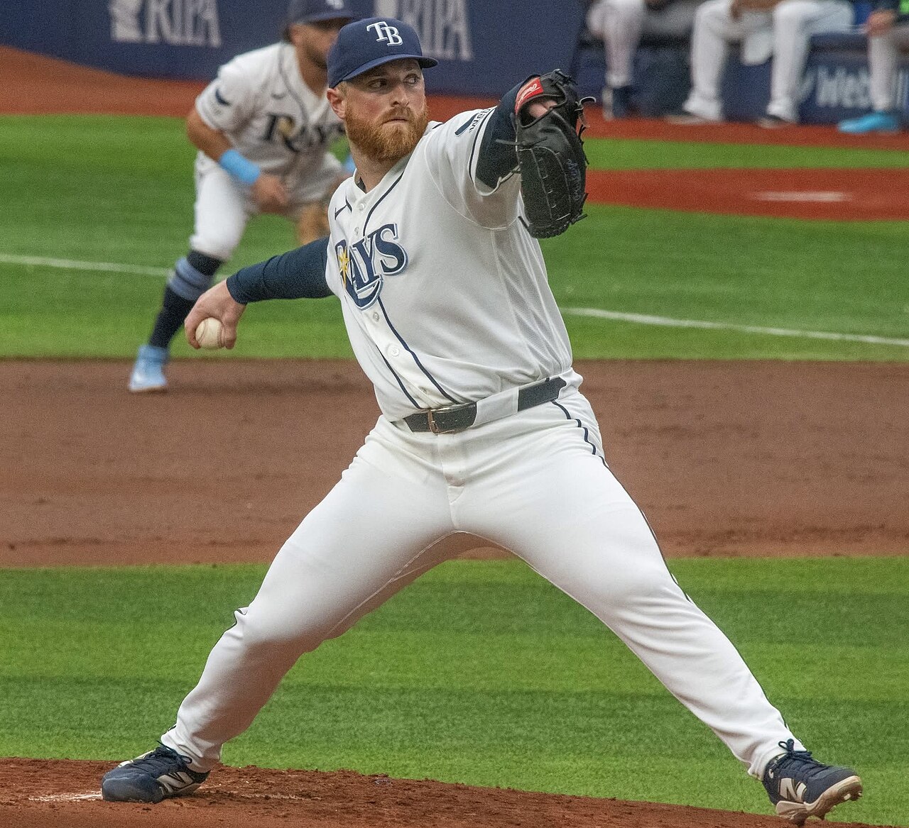Drew Rasmussen in a white Tampa Bay Rays uniform pitching on a baseball field