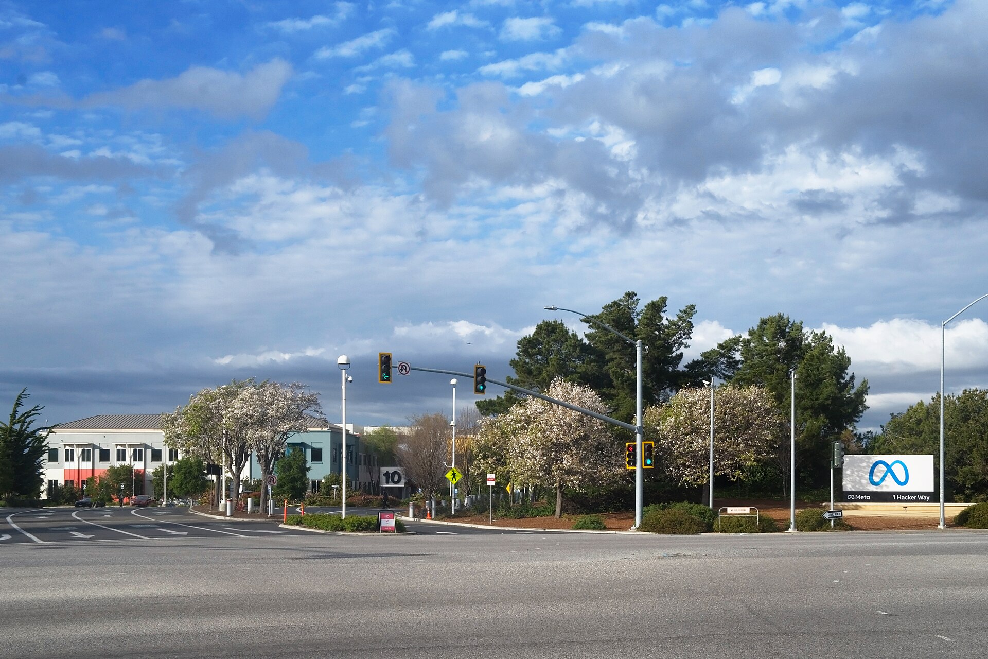 A Meta sign with the infinity logo and text 'Meta 1 Hacker Way' is visible on the right side of the image, with a building and trees in the background.