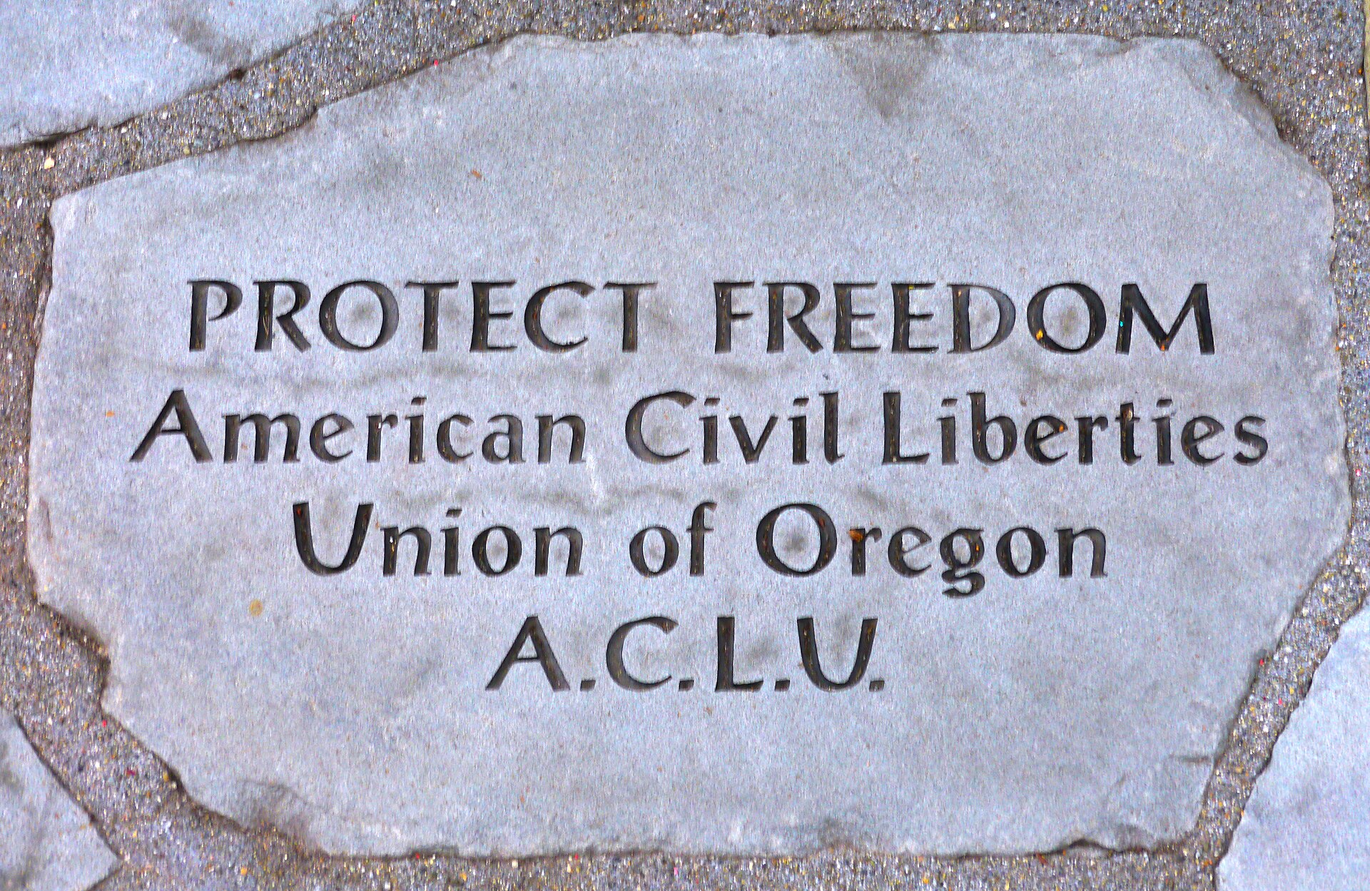 A stone plaque with carved text reading "PROTECT FREEDOM American Civil Liberties Union of Oregon A.C.L.U."